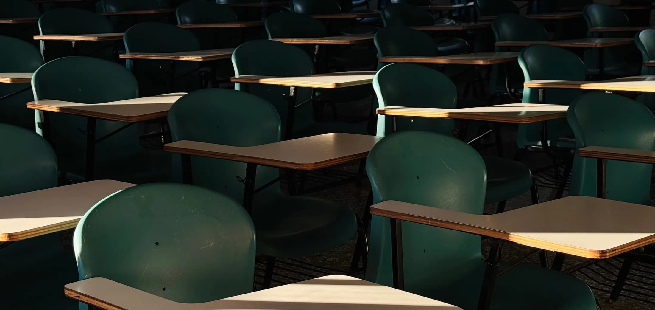 An empty exam room, rows of single tablet-arm desks set well apart from one another